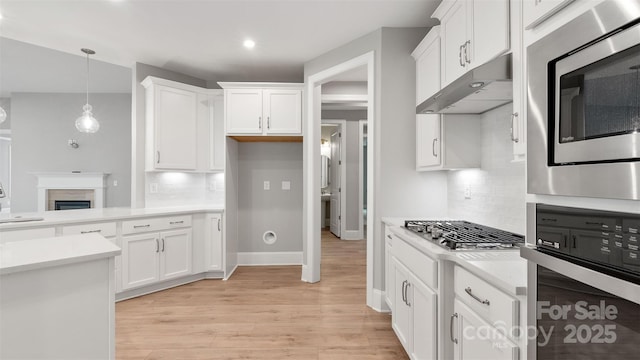 kitchen featuring white cabinets, under cabinet range hood, stainless steel appliances, and light countertops