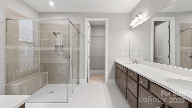 bathroom featuring double vanity, marble finish floor, a spacious closet, and a sink