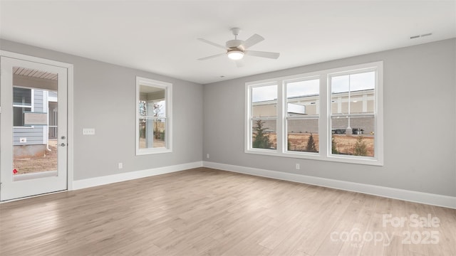 spare room featuring baseboards, a ceiling fan, visible vents, and light wood-style floors