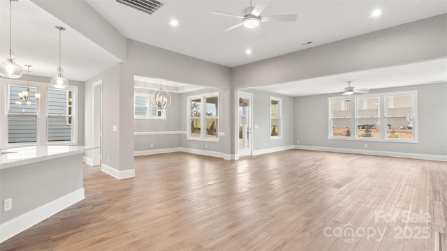 unfurnished living room featuring recessed lighting, visible vents, light wood-type flooring, baseboards, and ceiling fan with notable chandelier