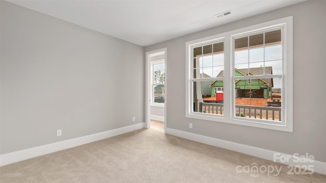 unfurnished room with baseboards, visible vents, and light colored carpet