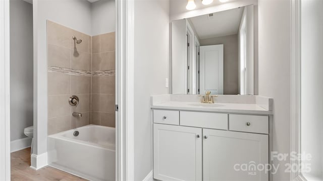 full bath with baseboards, toilet, wood finished floors, vanity, and shower / bathing tub combination