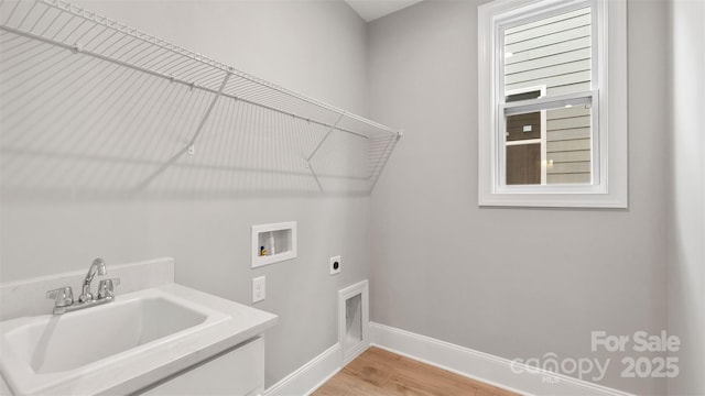 clothes washing area with laundry area, hookup for an electric dryer, light wood-type flooring, washer hookup, and a sink