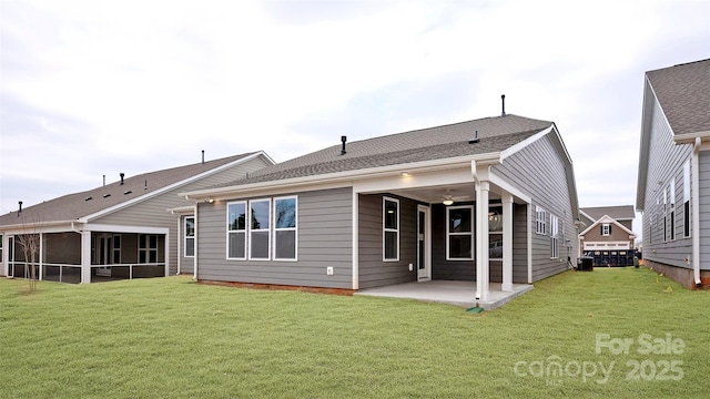 back of house featuring a patio, a yard, and roof with shingles