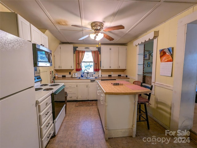 kitchen featuring sink, a center island, white cabinets, and white appliances