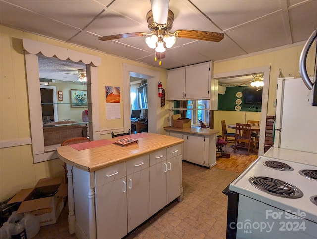 kitchen featuring a center island, white appliances, white cabinetry, and ceiling fan