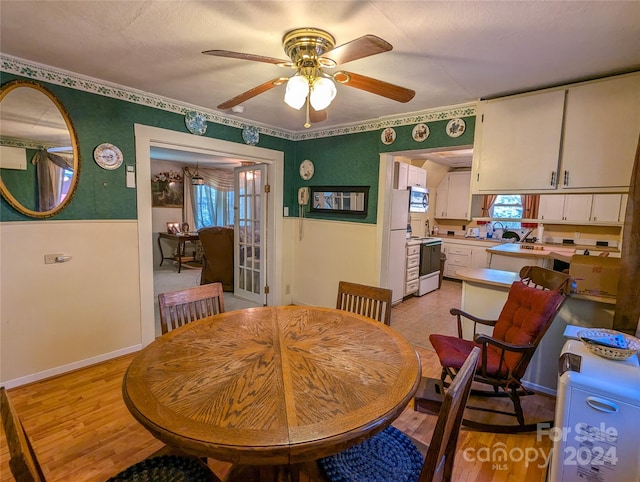 dining space featuring ceiling fan, sink, and light wood-type flooring