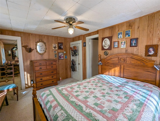 carpeted bedroom featuring a closet, ceiling fan, and wood walls