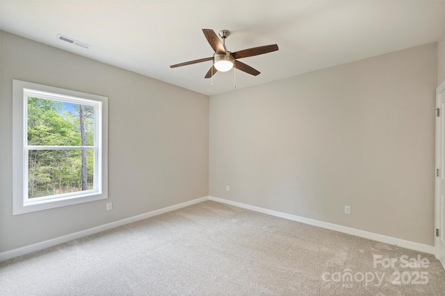 spare room with baseboards, a ceiling fan, and visible vents