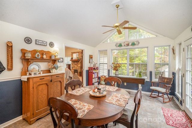 dining area featuring ceiling fan, a fireplace, and vaulted ceiling