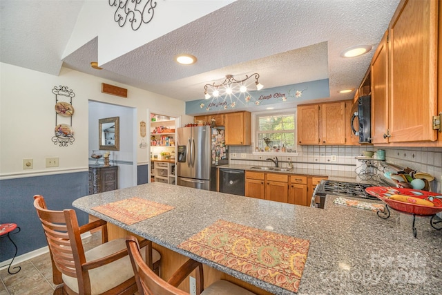 kitchen with kitchen peninsula, sink, a kitchen breakfast bar, black appliances, and a textured ceiling