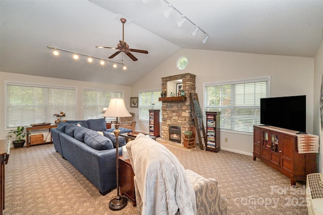 living room featuring lofted ceiling, light carpet, a stone fireplace, and ceiling fan