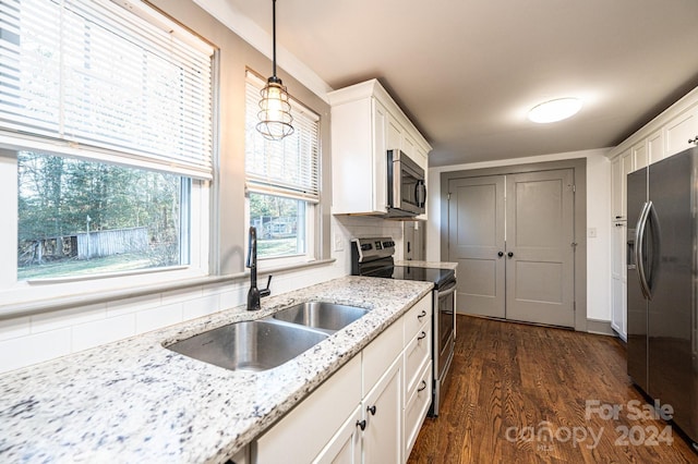 kitchen featuring dark wood-type flooring, sink, decorative light fixtures, white cabinetry, and stainless steel appliances