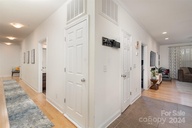 hall with ornamental molding and wood-type flooring