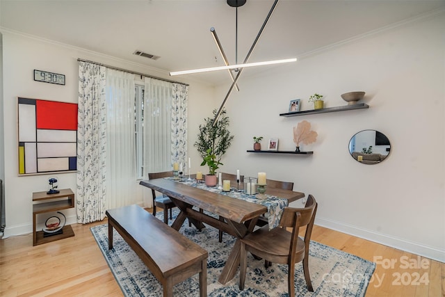 dining area featuring crown molding, an inviting chandelier, and light wood-type flooring