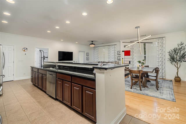 kitchen with light hardwood / wood-style floors, stainless steel appliances, dark brown cabinets, and an island with sink