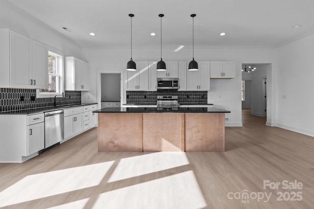 kitchen featuring hanging light fixtures, white cabinetry, a center island, and stainless steel appliances