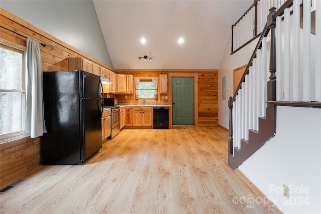 kitchen featuring black appliances, a wealth of natural light, and wooden walls