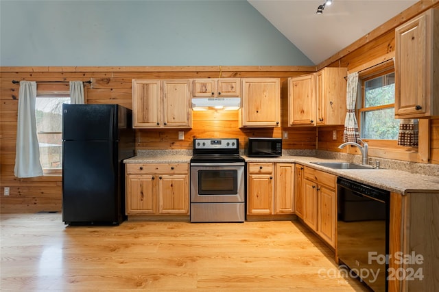 kitchen featuring wooden walls, black appliances, and a wealth of natural light