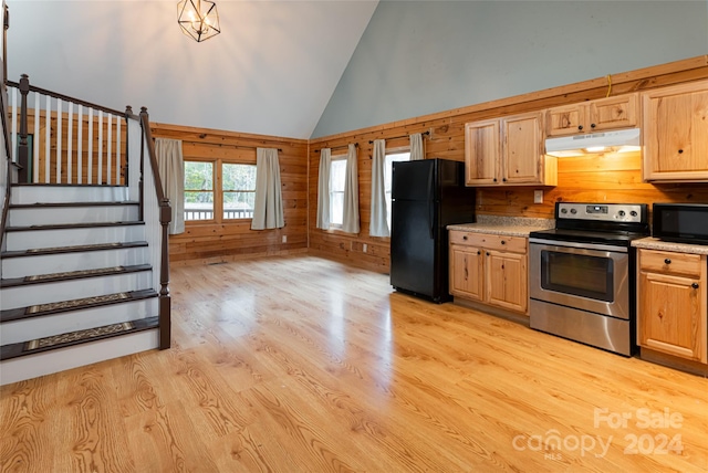 kitchen featuring light brown cabinets, high vaulted ceiling, light wood-type flooring, black appliances, and wooden walls