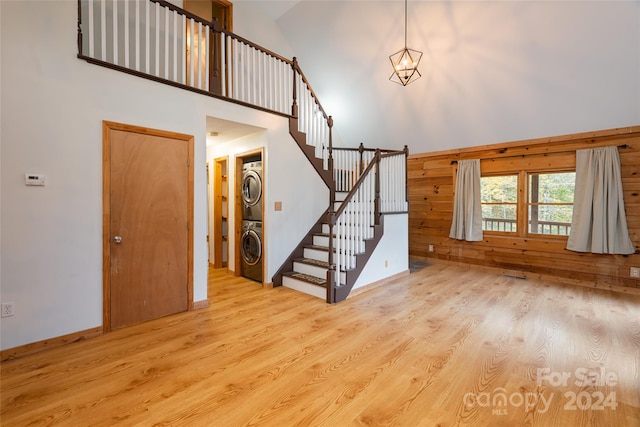 interior space with light wood-type flooring, high vaulted ceiling, and stacked washing maching and dryer