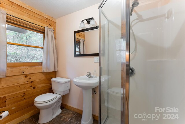 bathroom featuring toilet, wood walls, walk in shower, and tile patterned floors