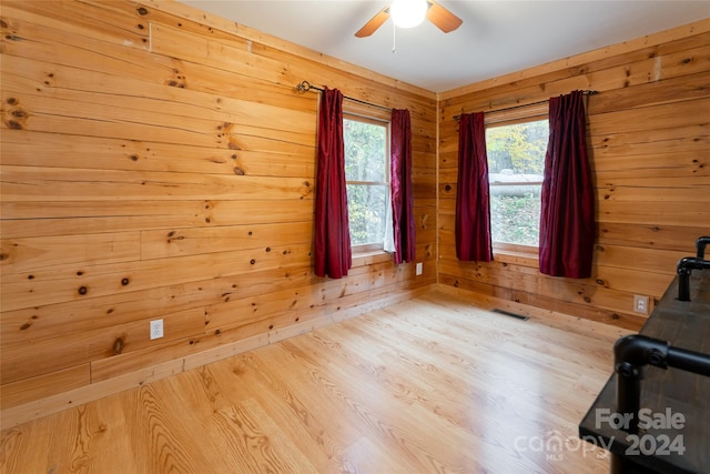 workout room featuring ceiling fan, light hardwood / wood-style flooring, and wooden walls