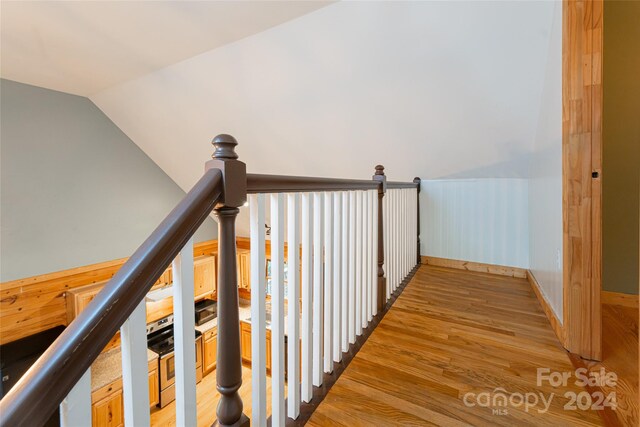 stairway featuring wooden walls, vaulted ceiling, and hardwood / wood-style flooring