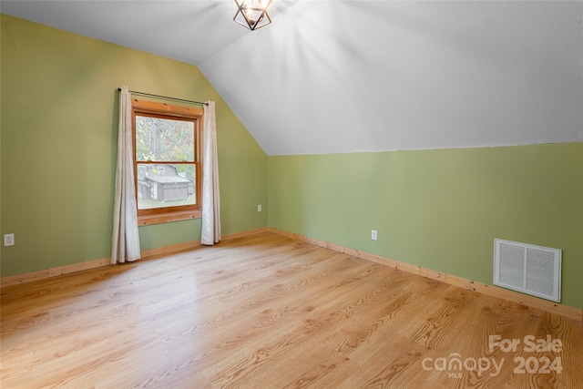 additional living space with light hardwood / wood-style floors and lofted ceiling