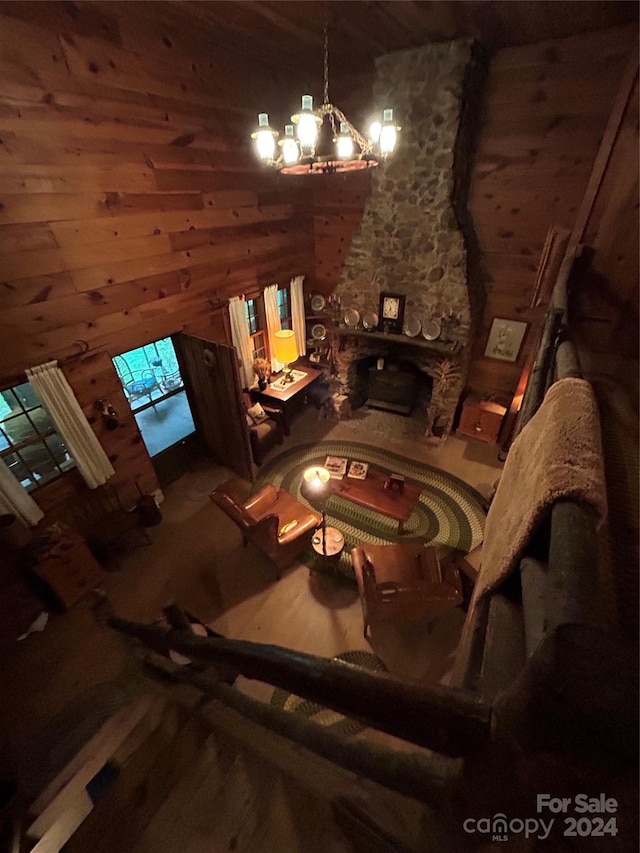 unfurnished living room featuring hardwood / wood-style floors, a notable chandelier, a stone fireplace, and wood walls