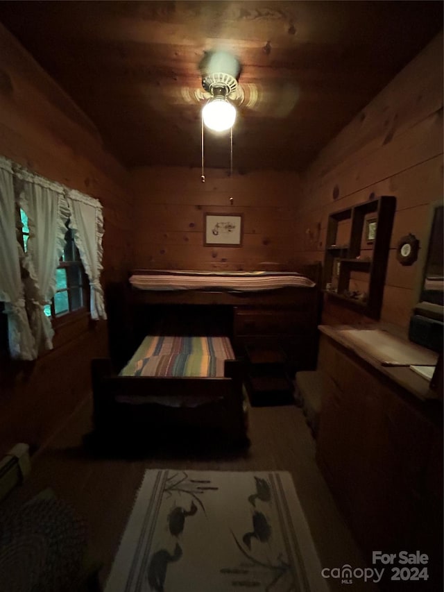 bedroom featuring ceiling fan and wood walls