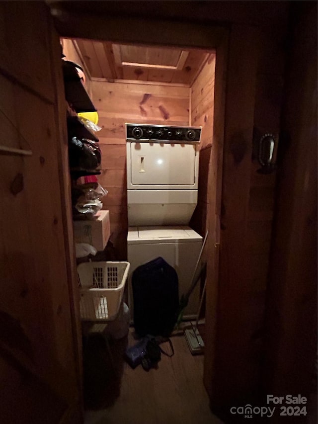 interior space featuring wood ceiling, stacked washer and clothes dryer, and wooden walls