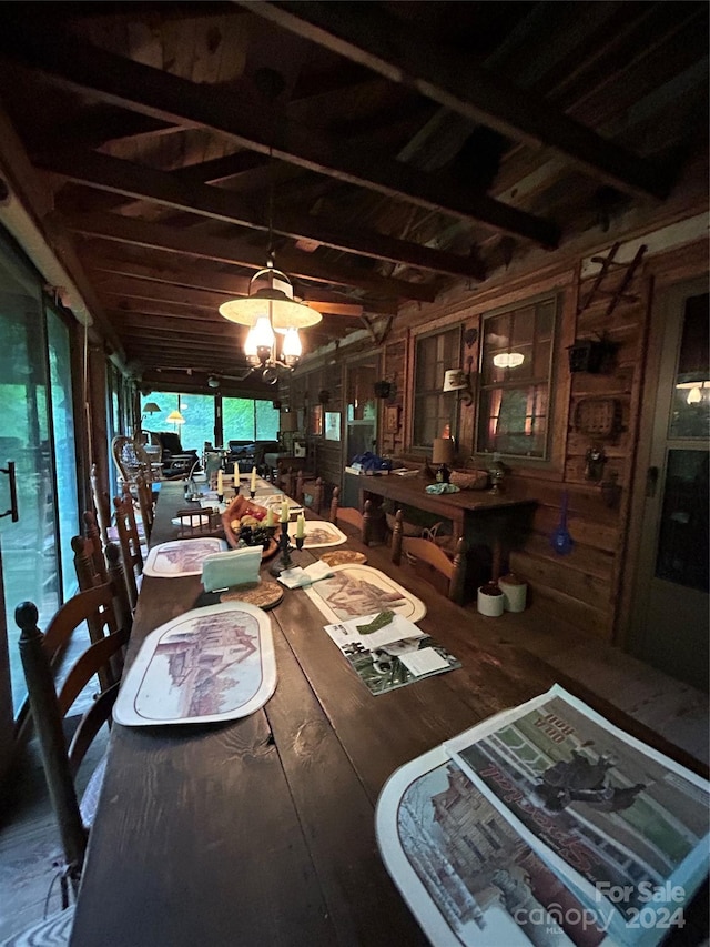 dining room featuring beam ceiling, a chandelier, wooden walls, and wood-type flooring