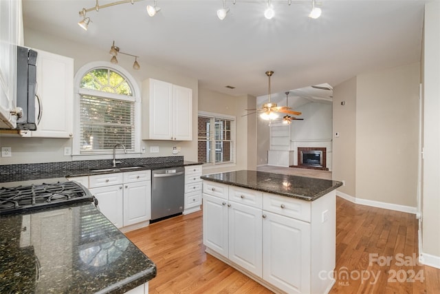 kitchen with sink, light wood-type flooring, appliances with stainless steel finishes, a kitchen island, and white cabinetry