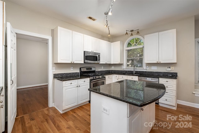 kitchen featuring white cabinetry, dark stone counters, light hardwood / wood-style floors, a kitchen island, and appliances with stainless steel finishes