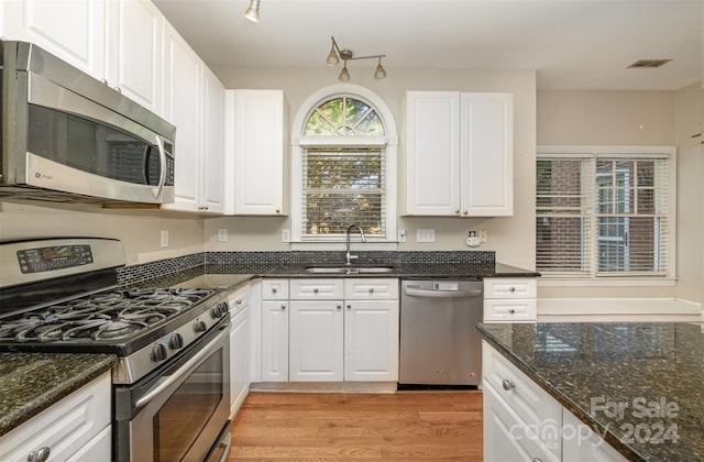 kitchen with white cabinetry, sink, stainless steel appliances, and light hardwood / wood-style floors