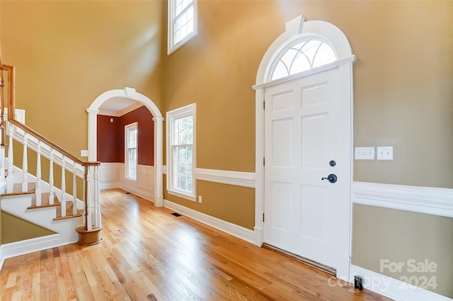 foyer with a high ceiling, light wood-type flooring, and a healthy amount of sunlight