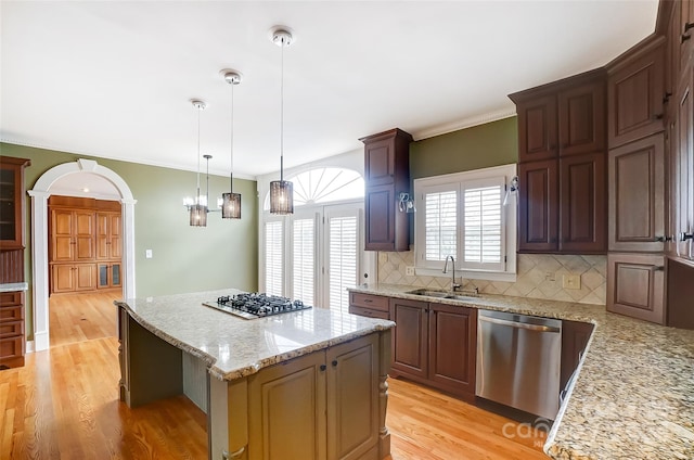 kitchen featuring tasteful backsplash, stainless steel appliances, sink, light hardwood / wood-style flooring, and a kitchen island