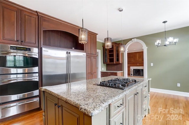 kitchen featuring white cabinetry, pendant lighting, stainless steel appliances, and light wood-type flooring