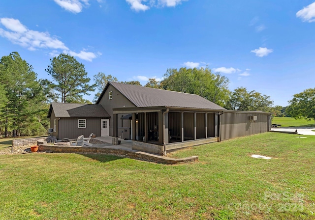 back of property featuring a lawn, a sunroom, and a patio area