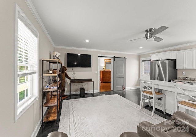 living room with plenty of natural light, dark wood-type flooring, a barn door, and ceiling fan