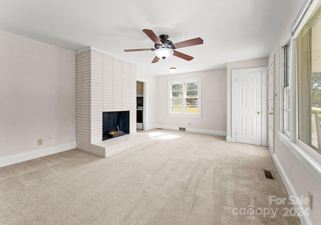 unfurnished living room with a fireplace, light carpet, and ceiling fan