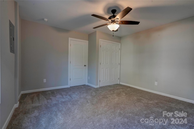 unfurnished bedroom with a closet, electric panel, ceiling fan, and carpet flooring