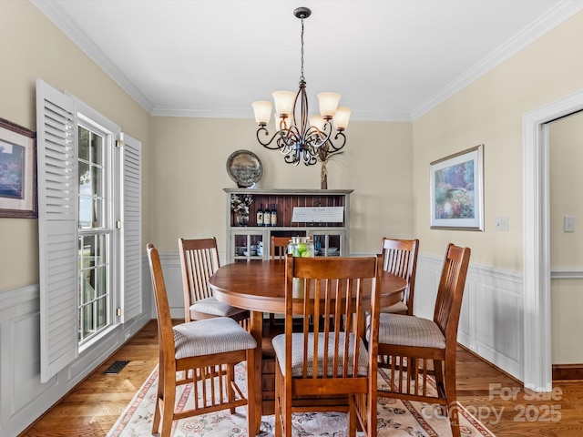 dining room featuring a chandelier, hardwood / wood-style flooring, and ornamental molding