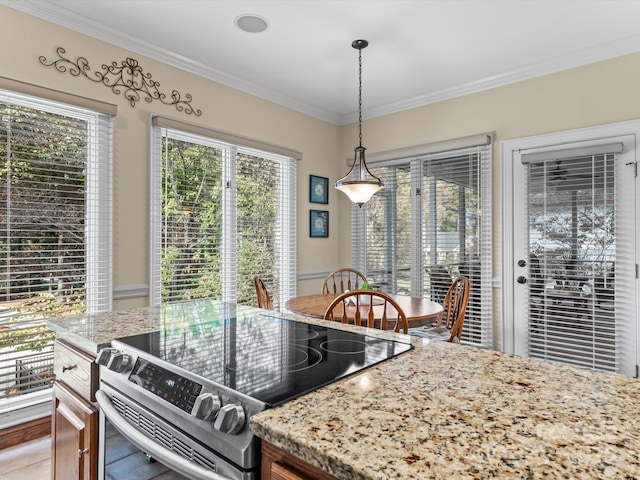 kitchen with light stone countertops, range, decorative light fixtures, and a healthy amount of sunlight