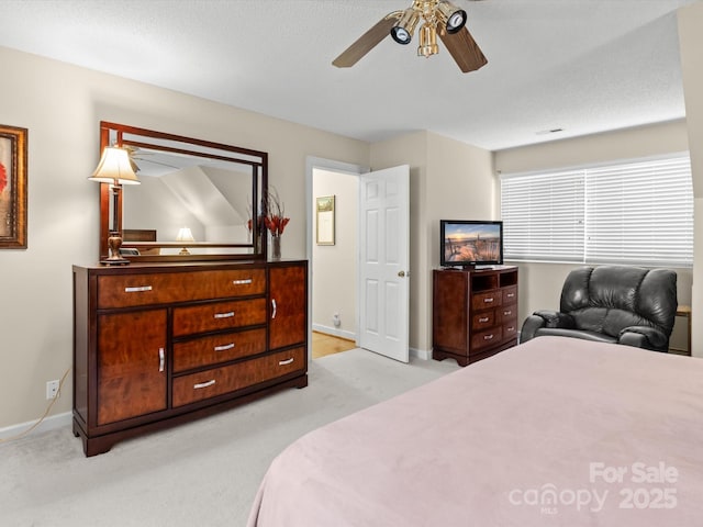 bedroom featuring a textured ceiling, light colored carpet, and ceiling fan