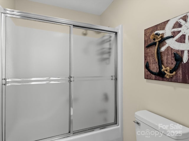 bathroom featuring bath / shower combo with glass door and toilet