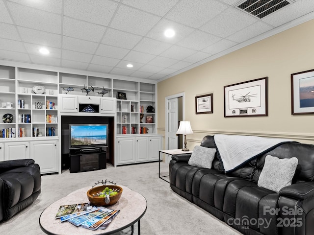 carpeted living room with built in shelves, a paneled ceiling, and crown molding