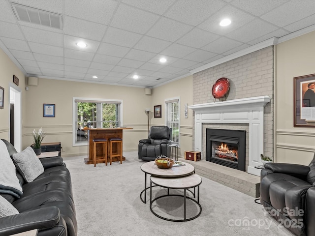 carpeted living room featuring a paneled ceiling, crown molding, and a brick fireplace