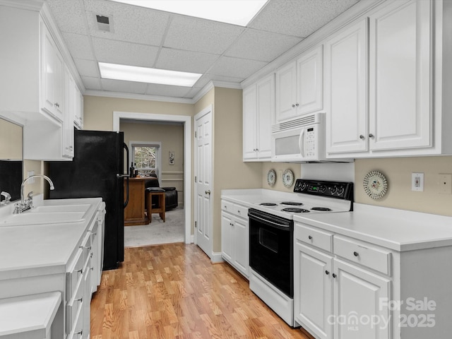 kitchen with a drop ceiling, white appliances, white cabinets, sink, and light hardwood / wood-style floors